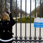 Una mujer toma una instantánea desde una de las puertas del parque del Retiro, cerrado por el Ayuntamiento de Madrid y que reabrirá hoy sus puertas