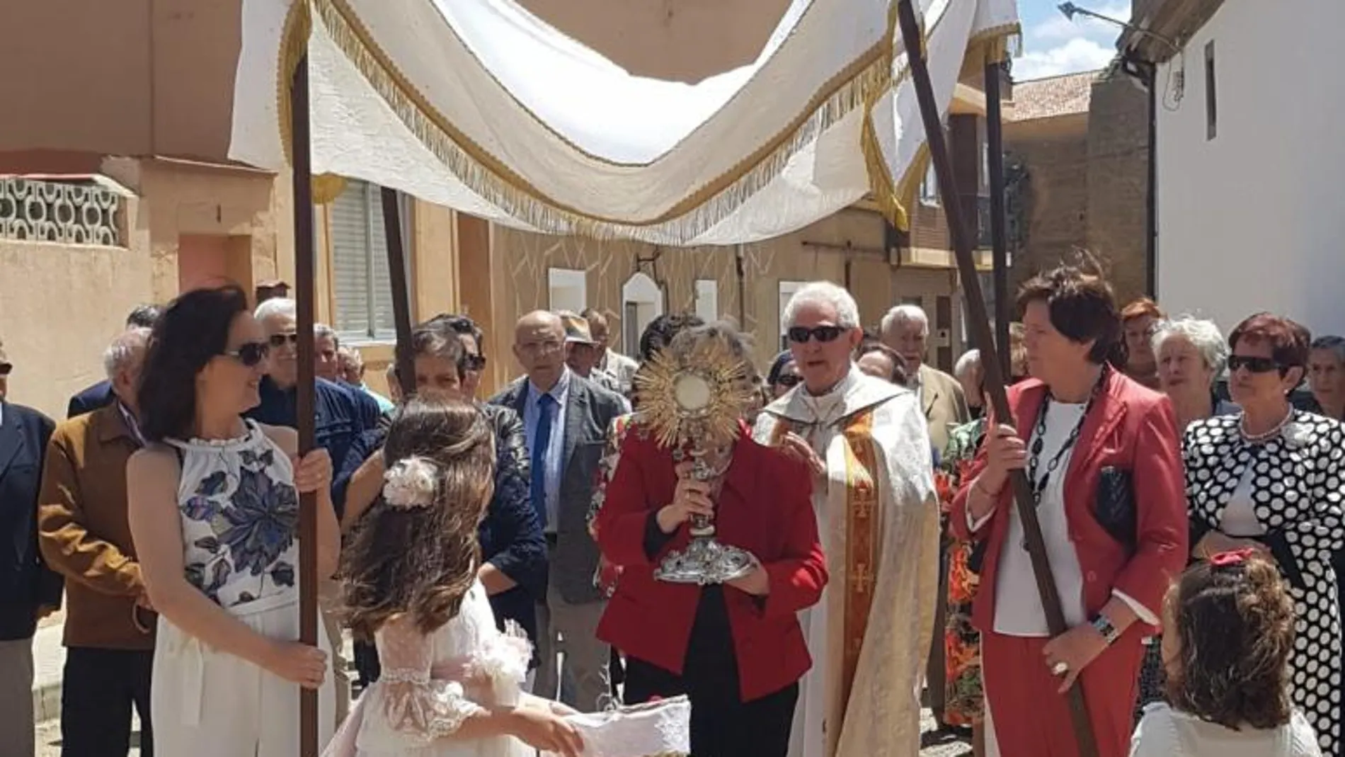 Mujeres de la localidad cargan con la custodia en la procesión del Corpus acompañadas de la pequeña que tomó su Primera Comunión