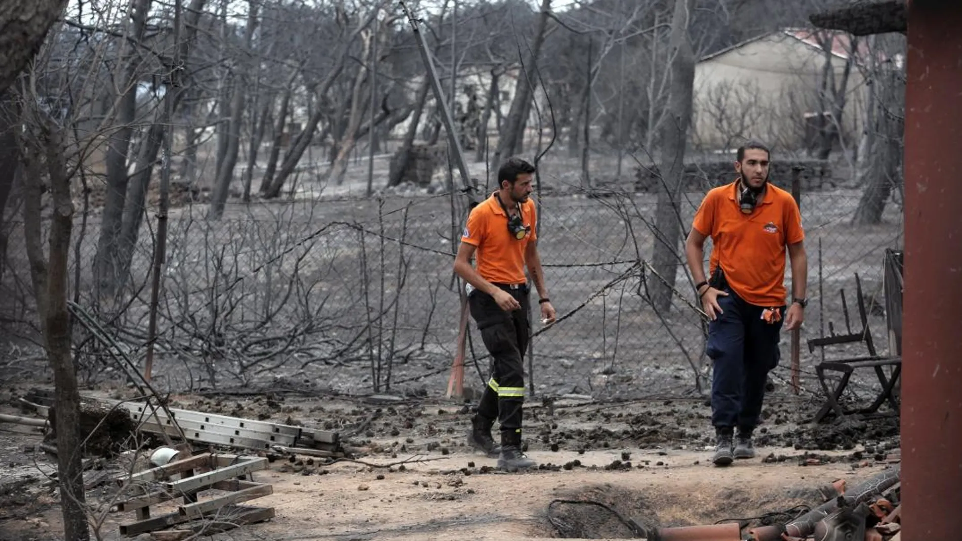 Dos miembros de personal de rescate buscan a posibles víctimas en una zona afectada por los incendios en Mati, Ática (Grecia) / Foto: Efe