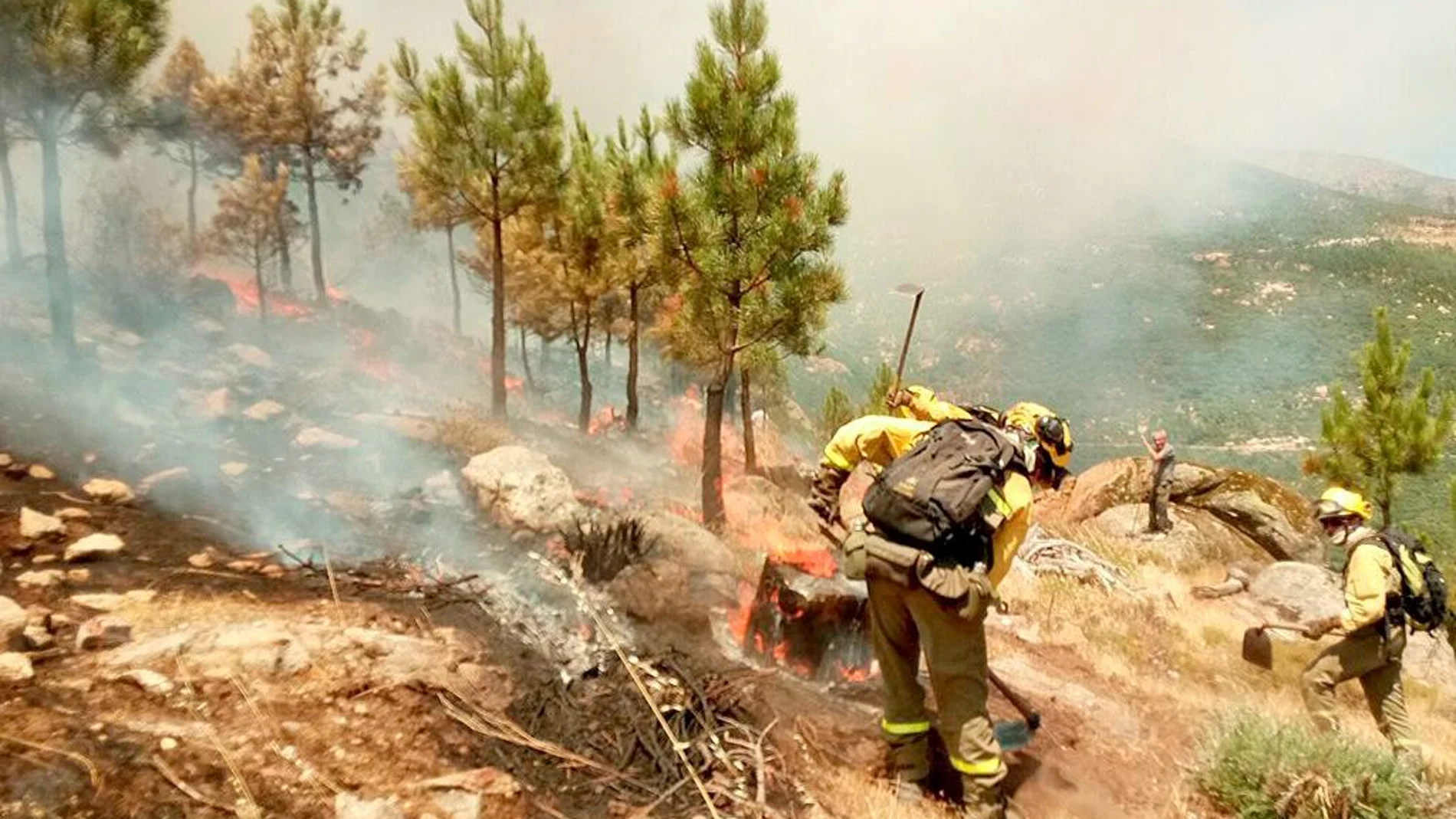 Operarios del servicio de extinción de incendios trabajan para sofocar las llamas en el fuego de Casavieja, en el valle del Tiétar