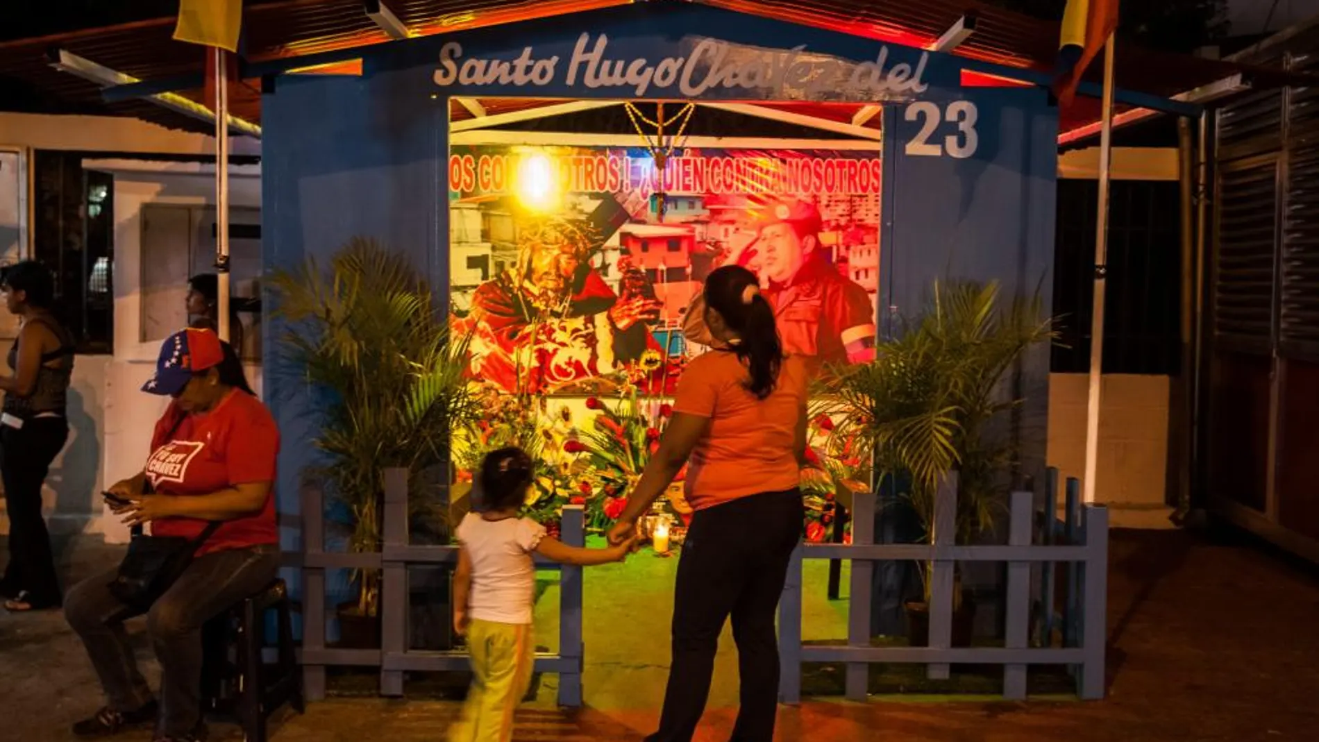 Fotografía que muestra a unos visitantes en la pequeña e improvisada capilla en honor a "Santo Hugo Chávez del 23", en el combativo barrio del 23 de Enero de Caracas (Venezuela),