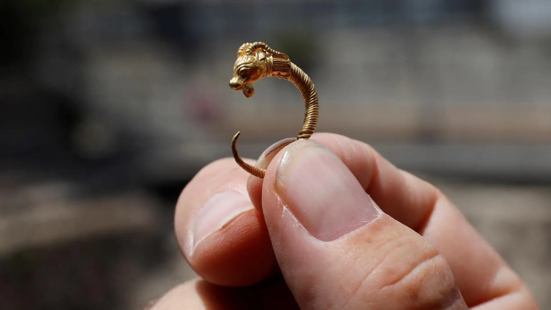 Un arqueólogo israelí sujeta el pendiente de oro del período Helenístico