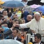 El Papa Francisco saluda a los miles de peregrinos que aguardaban con paraguas bajo la lluvia para asistir a la audiencia general de todos los miércoles