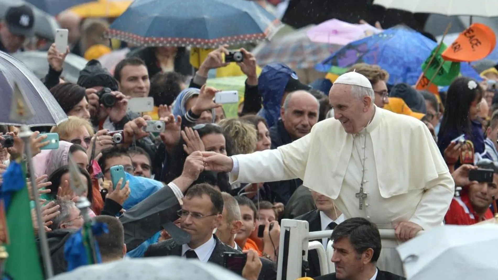 El Papa Francisco saluda a los miles de peregrinos que aguardaban con paraguas bajo la lluvia para asistir a la audiencia general de todos los miércoles
