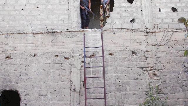 Dos rebeldes sirios toman posiciones en un edificio y vigilan a las tropas enemigas en la localidad de Deir al Zor