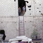 Dos rebeldes sirios toman posiciones en un edificio y vigilan a las tropas enemigas en la localidad de Deir al Zor