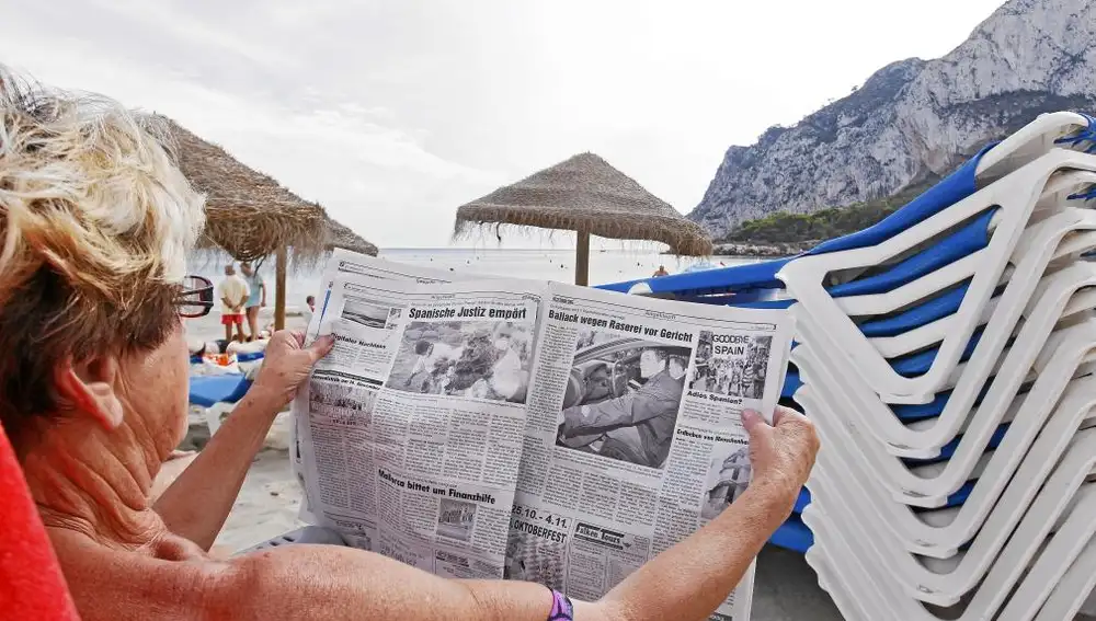Una mujer alemana lee un periódico en las playas de Denia