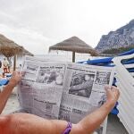 Una mujer alemana lee un periódico en las playas de Denia