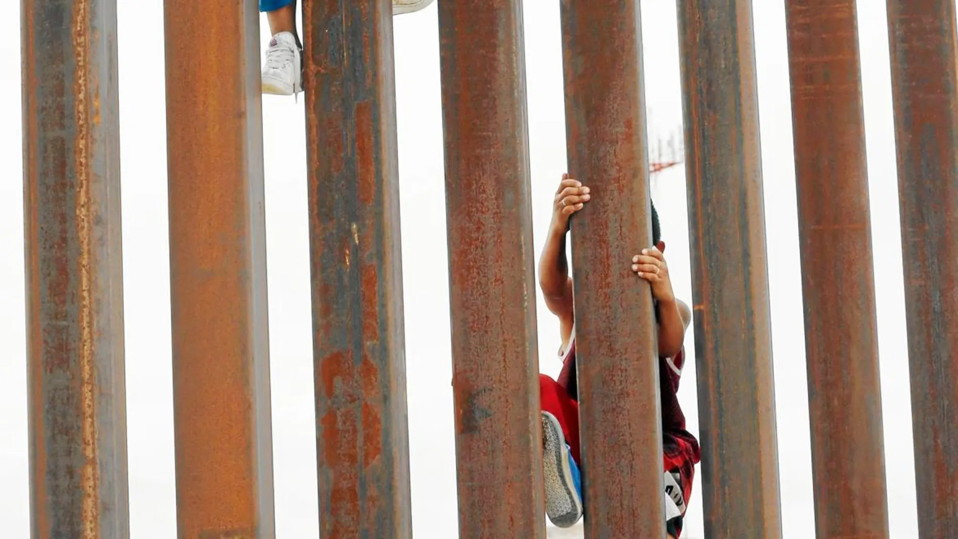 Niños de la localidad mexicana de Anapra trepan por una de las secciones del muro que marca la frontera entre los dos países/Ap