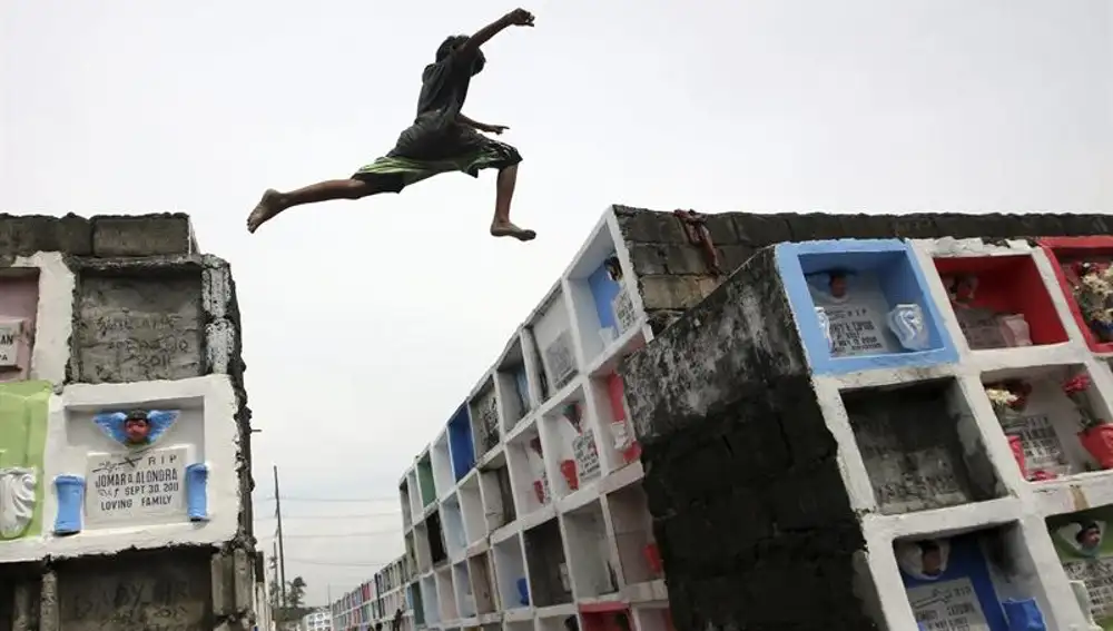 Un muchacho filipino salta entre dos bloques de nichos en un cementerio público en Paranaque, sur de Manila (Filipinas).