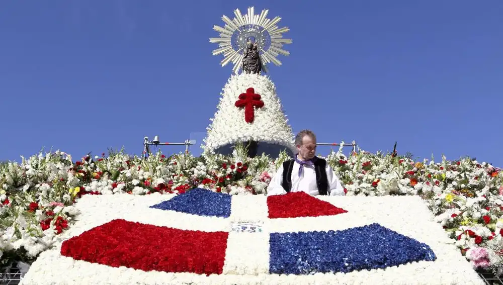 Una ofrenda de flores con la bandera de Santo Domingo destaca sobre el tradicional y colorido manto de la Vírgen del Pilar