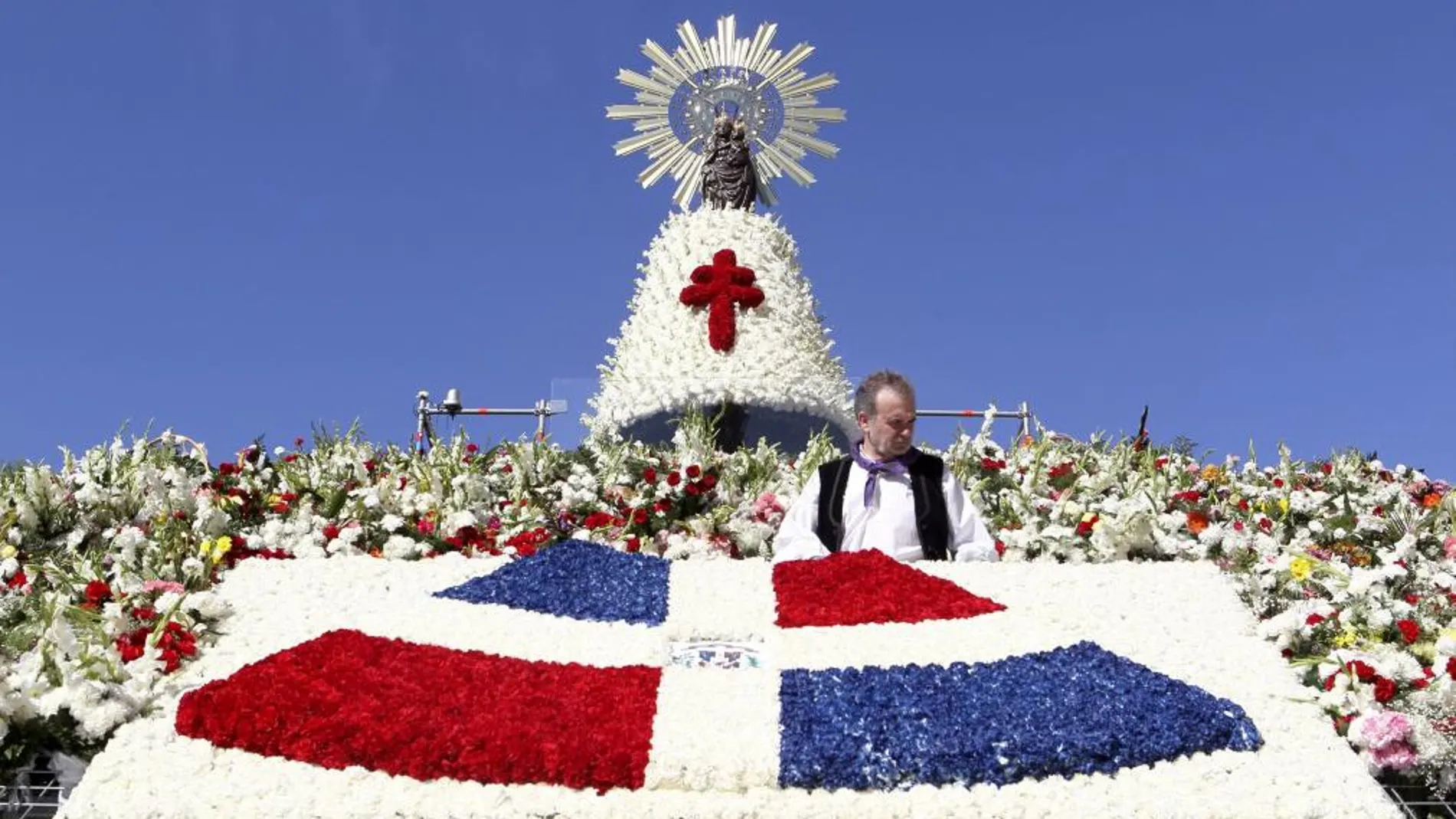 Una ofrenda de flores con la bandera de Santo Domingo destaca sobre el tradicional y colorido manto de la Vírgen del Pilar