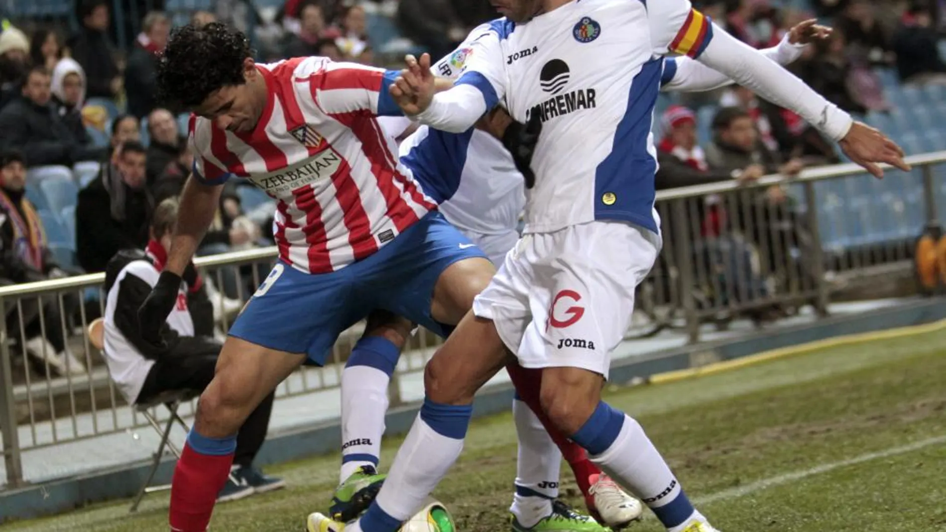 El delantero brasileño del Atlético de Madrid Diego Costa (i) pelea un balón con Miguel Torres (d), del Getafe, durante el partido de ida de los octavos de la final de la Copa del Rey que están disputando esta noche en el estadio Vicente Calderón, en Madrid.