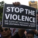 Varios manifestantes sostienen retratos del depuesto presidente egipcio Mohamed Mursi y carteles de apoyo durante una manifestación convocada cerca de la embajada de Egipto