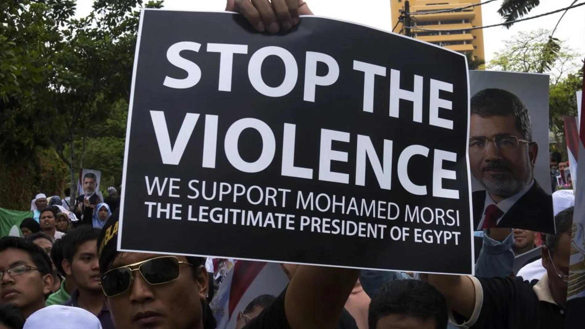 Varios manifestantes sostienen retratos del depuesto presidente egipcio Mohamed Mursi y carteles de apoyo durante una manifestación convocada cerca de la embajada de Egipto
