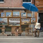 El "stand"supuestamente improvisado en Venecia por Banksy, que se esconde tras un periódico