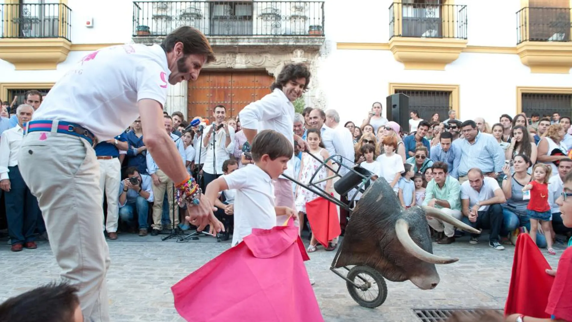 Padilla ayuda con el capote a un niño en presencia de Morante, preparado para embestir con el carretón