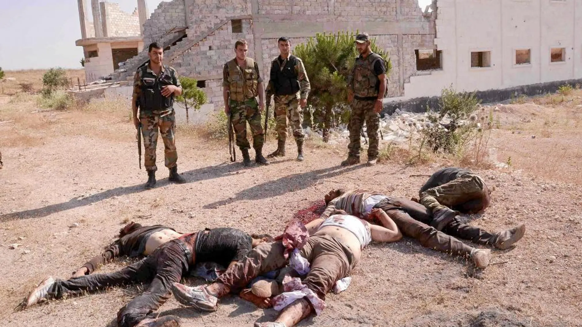 Combatientes leales a Asad posan frente a los cadáveres de miembros del Ejército Libre Sirio, ayer, en Alepo