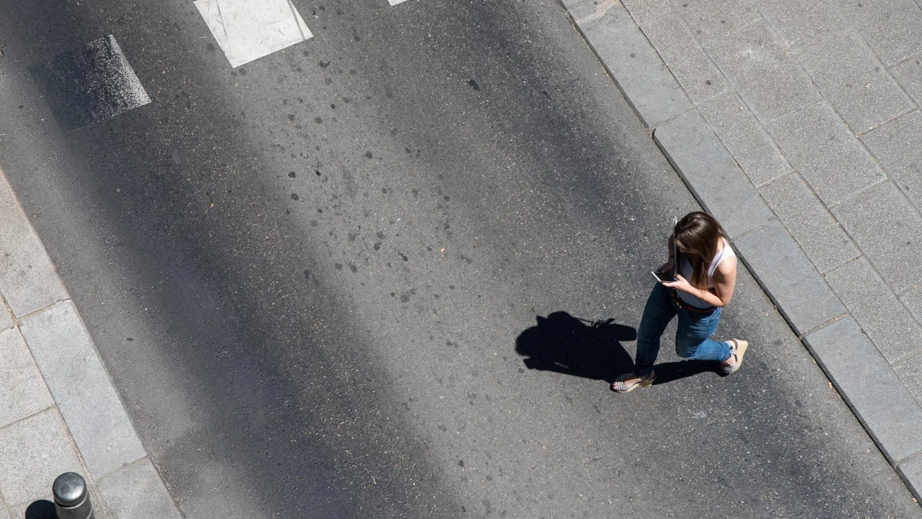 Una joven cruza la calle por lugar indebido mientras consulta el móvil / David Jar