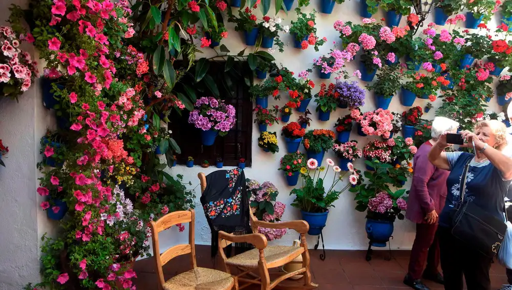Varias personas visitan un patio de la calle Tinte de Córdoba, con sus coloristas macetas con flores / Foto: Efe
