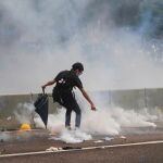 Un manifestante trata de apagar las bombas de gas lacrimógeno disparadas por la policía de Hong Kong en las manifestaciones de hoy/Ap