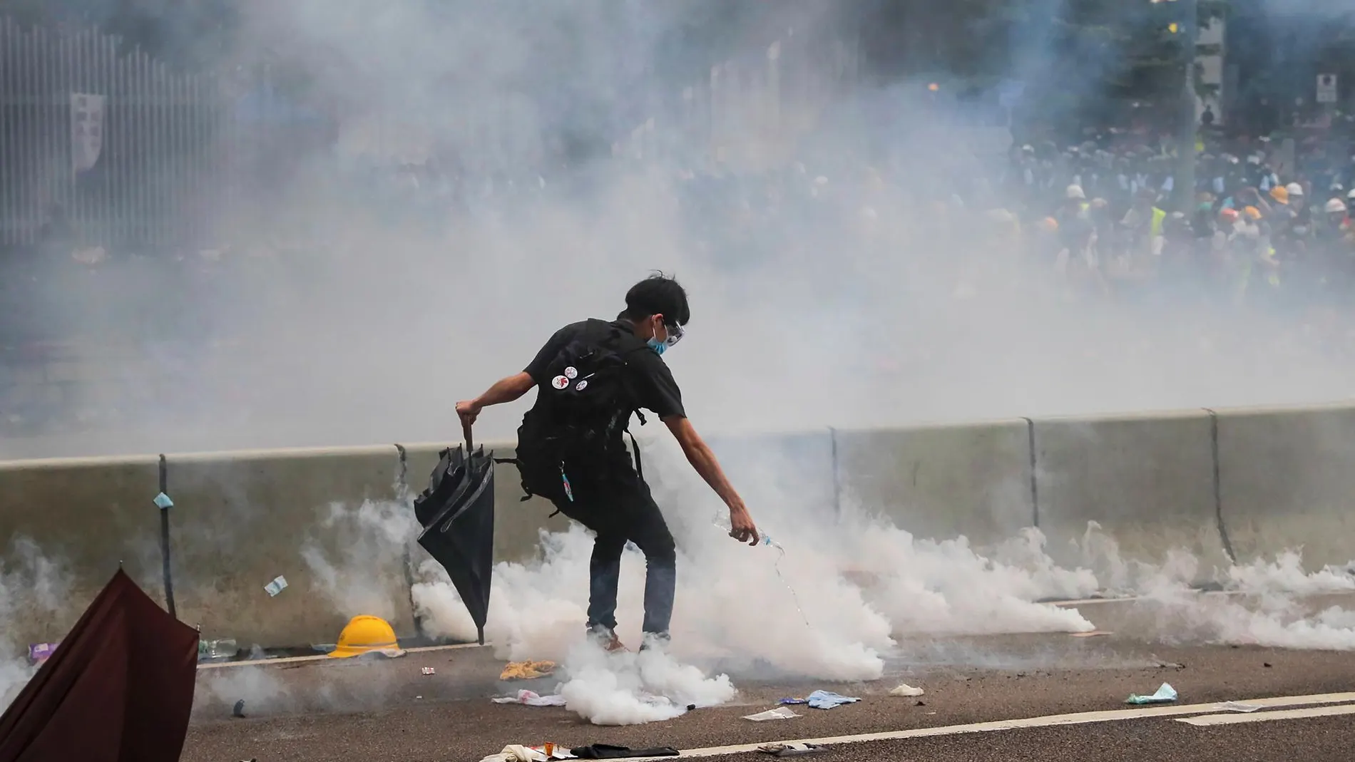 Un manifestante trata de apagar las bombas de gas lacrimógeno disparadas por la policía de Hong Kong en las manifestaciones de hoy/Ap