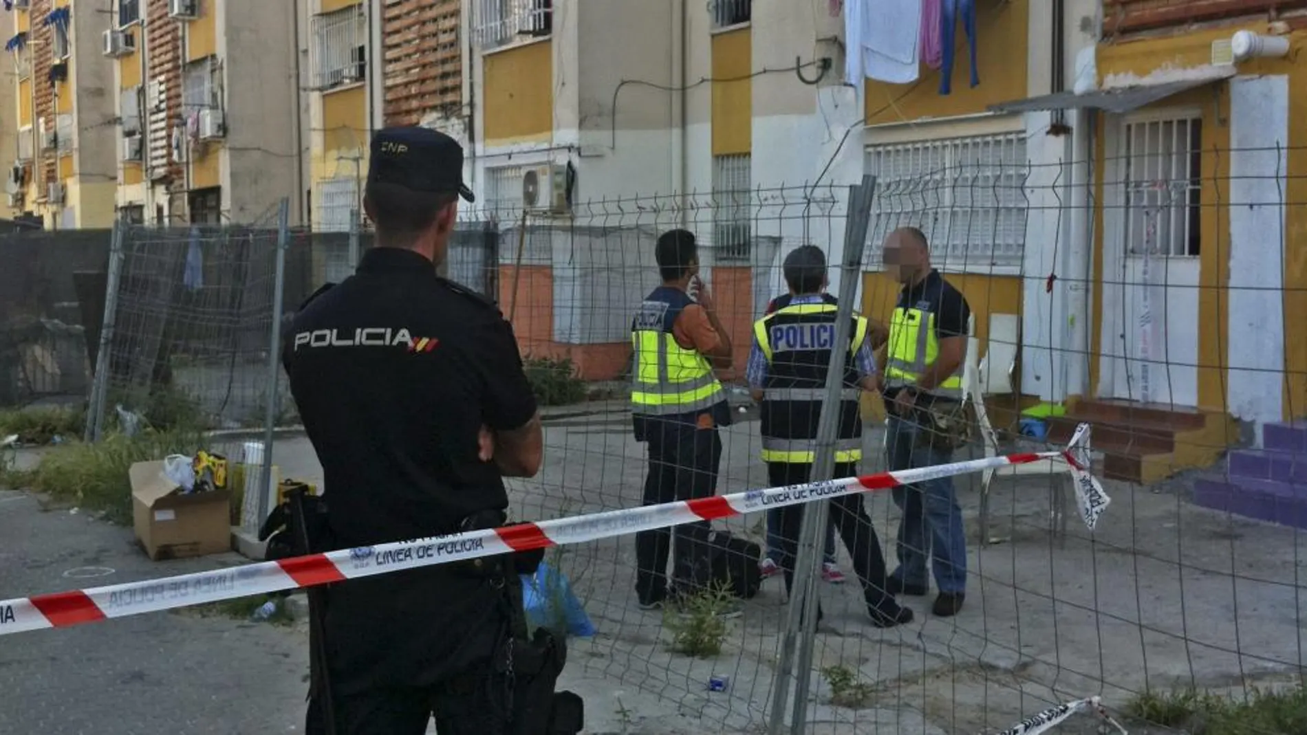 Miembros de la Policía Nacional ante la fachada del edificio donde una niña de 7 años ha resultado muerta en un tiroteo registrado esta madrugada en la barriada de las Tres Mil Viviendas de Sevilla.