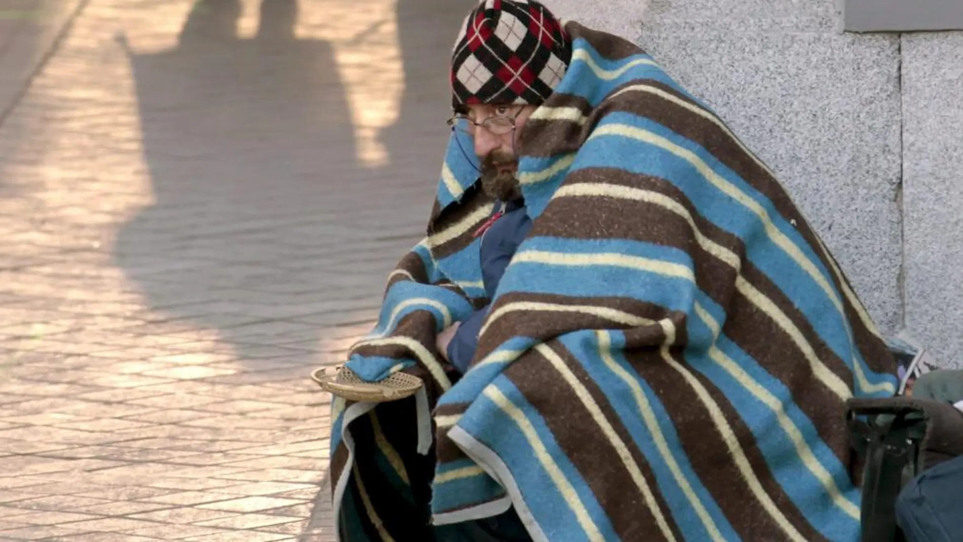 Un mendigo se protege con una manta en Madrid