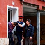 Un Mosso d'Esquadra custodia a uno de los dos detenidos en Cornellà de Llobregat (Barcelona) por su supuesta relación con la desaparición de Janet Jumillas,