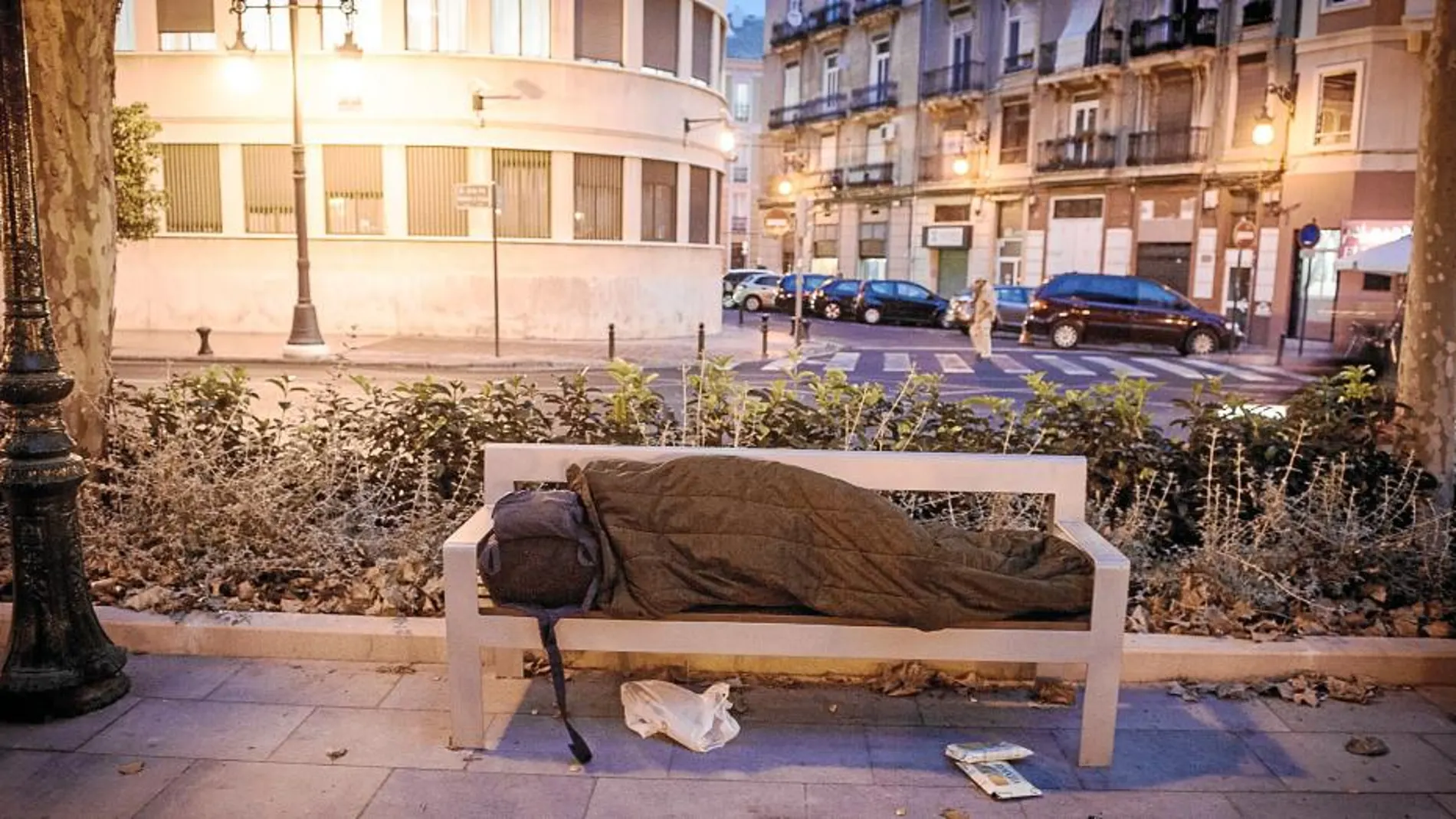 Una persona sin hogar descansa en un banco de la Gran Vía Ramón y Cajal de Valencia