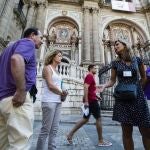 Una guía oficial muestra a un grupo de turistas la catedral de Málaga