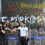 Policías turcos antidisturbios delante de una sucursal bancaria dañada en la plaza Taksim de Estambul