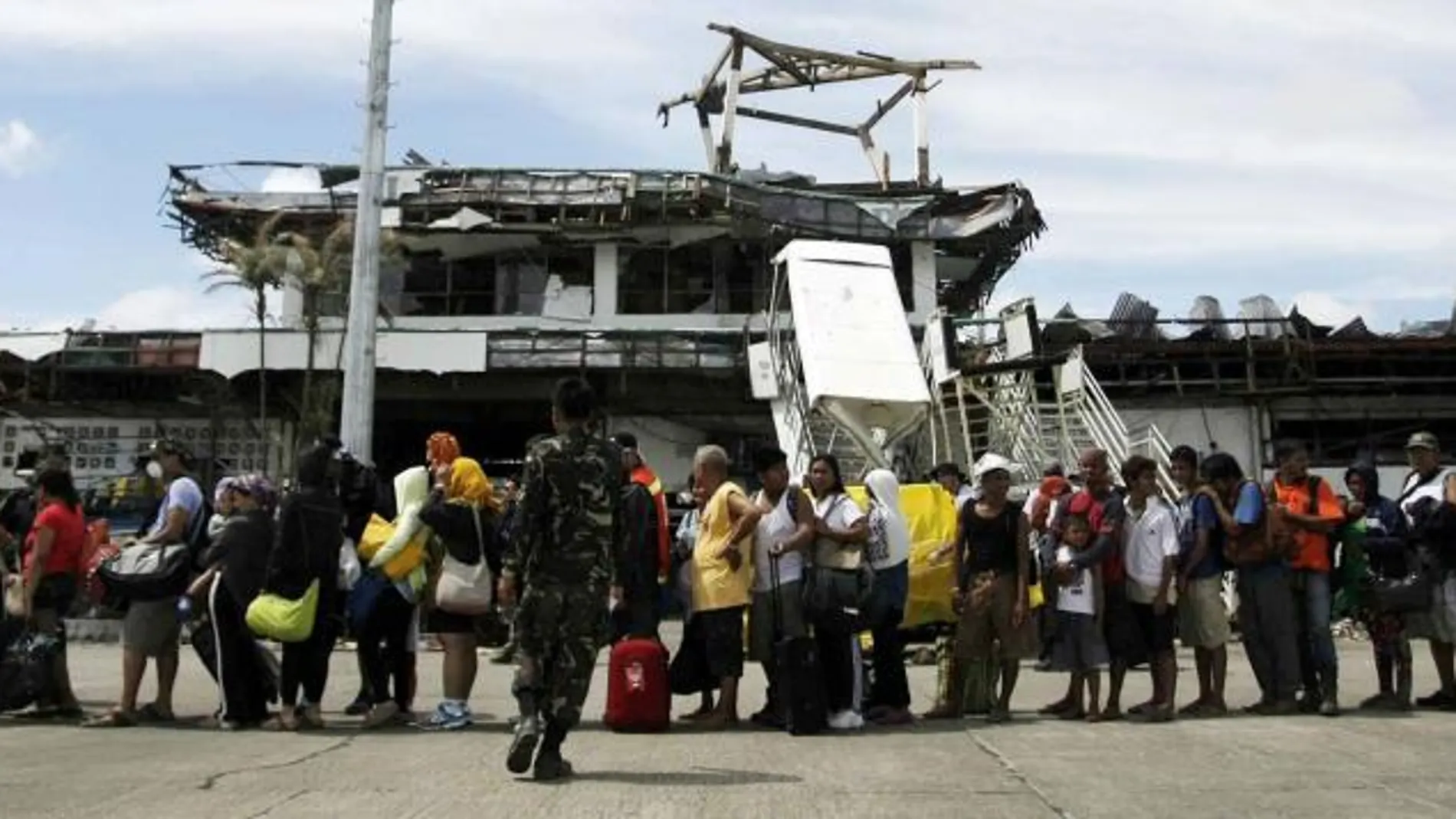 Varias personas esperan la llegada de un avión de rescate en el aeropuerto de Tacloban (Filipinas) hoy, miércoles 13 de noviembre