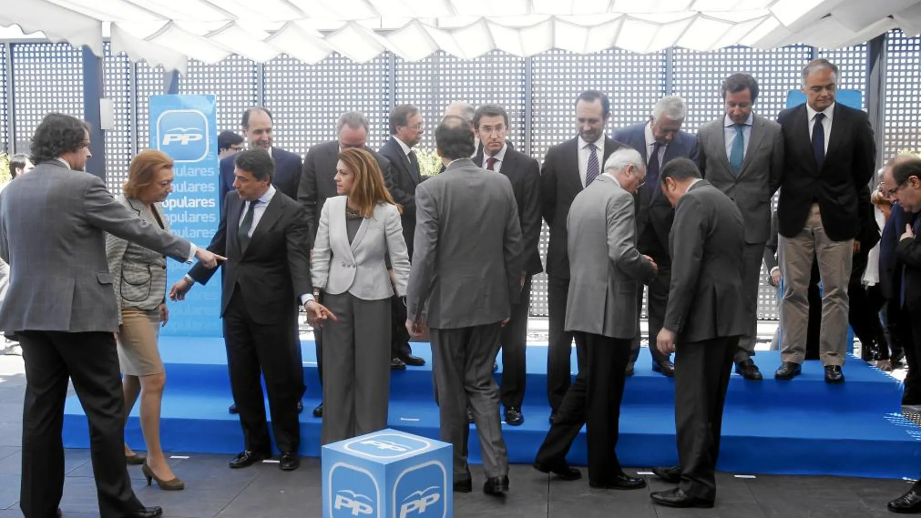 Rajoy, de espaldas, se dirige hacia su lugar junto a Cospedal mientras a Luisa Fernanda Rudi le indican dónde debe situarse