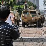 Un manifestante cuelga un papel en una alambrada junto a los militares