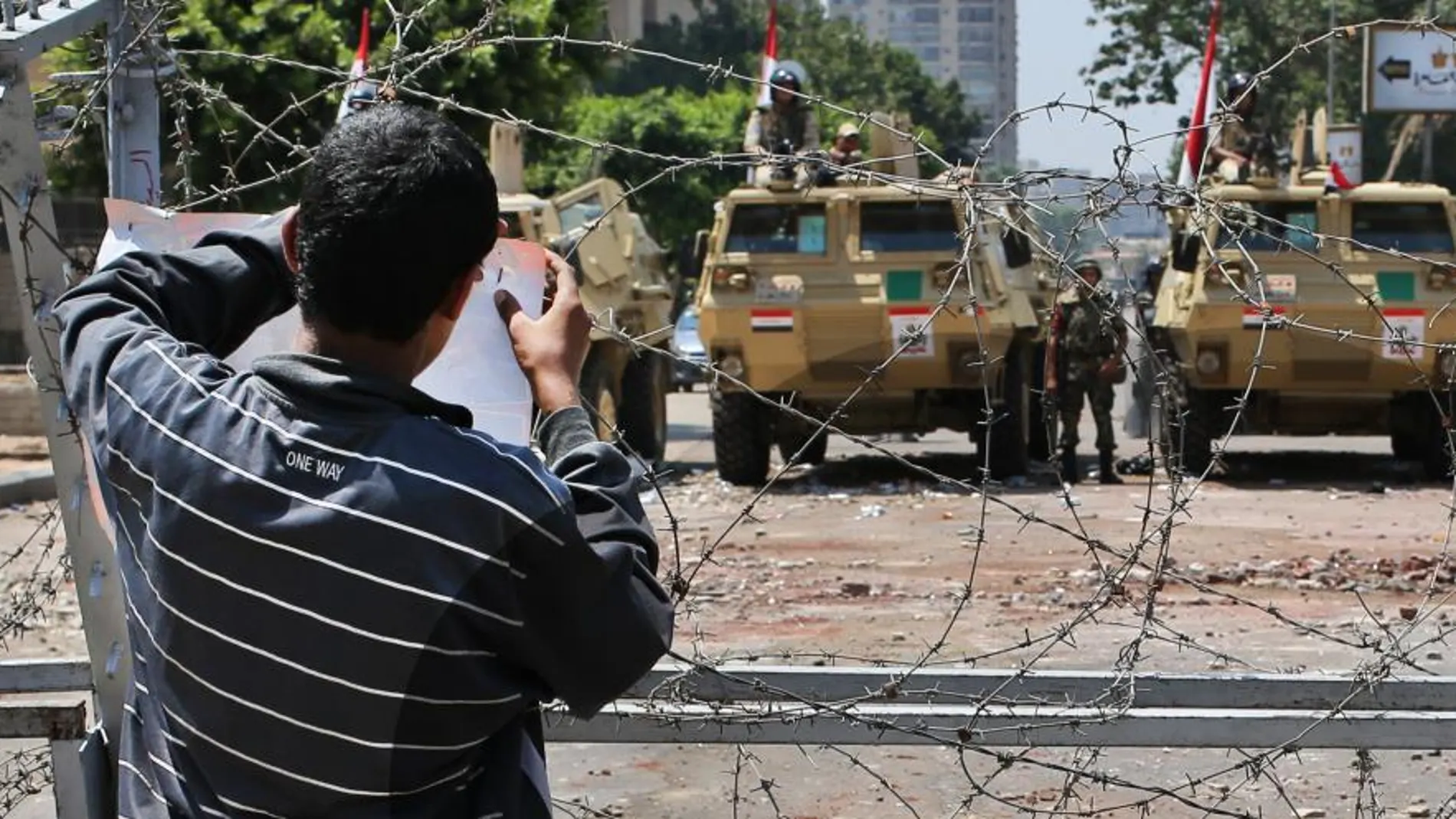 Un manifestante cuelga un papel en una alambrada junto a los militares