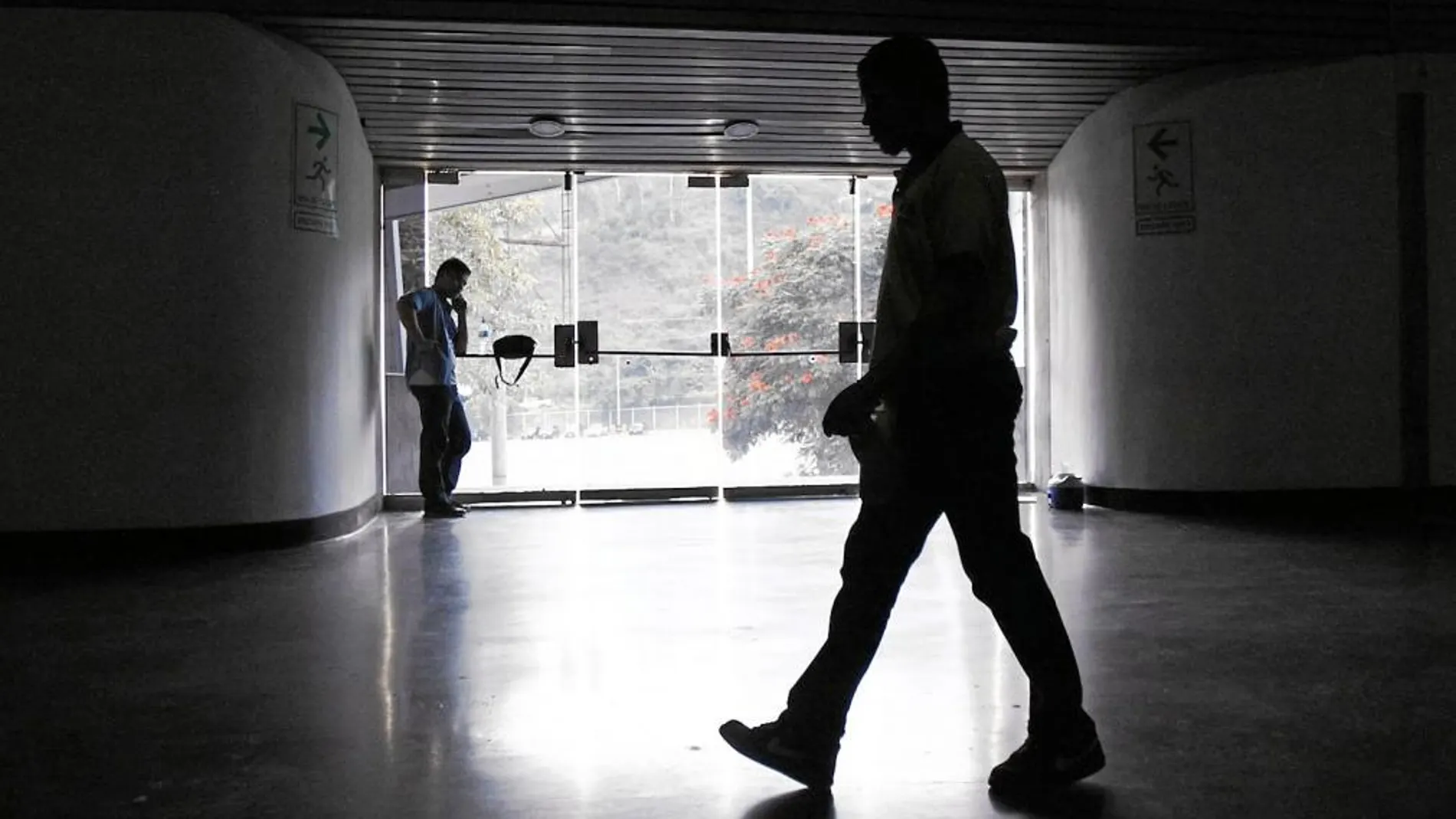 Un vigilante de seguridad camina a oscuras en un centro deportivo afectado por el apagón eléctrico en Caracas