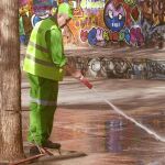 Un barrendero limpia con una manguera una calle de Barcelona
