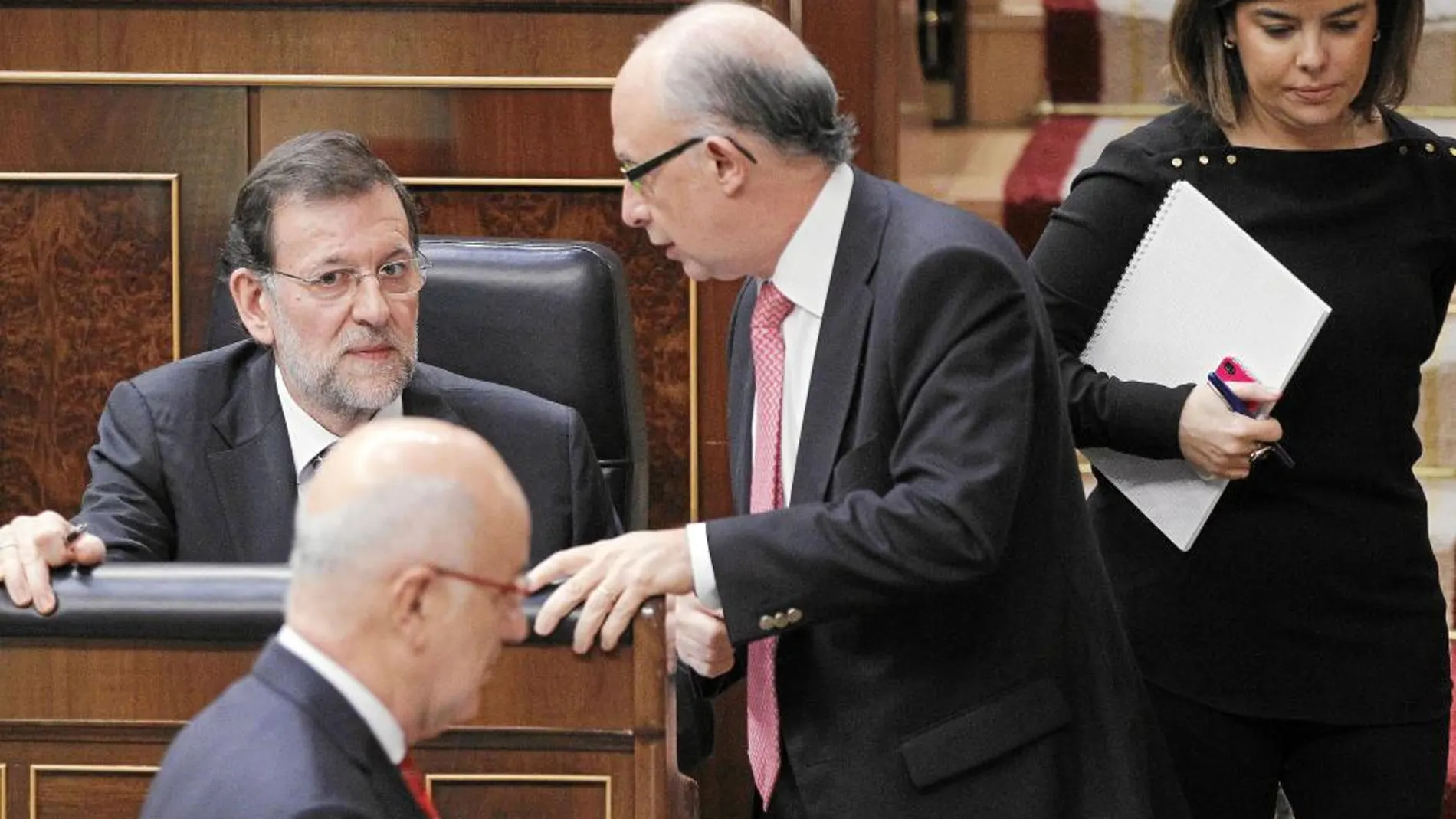Duran Lleida pasa por delante de Mariano Rajoy y Cristóbal Montoro mientras conversan en el hemiciclo. Al lado, Sáenz de Santamaría