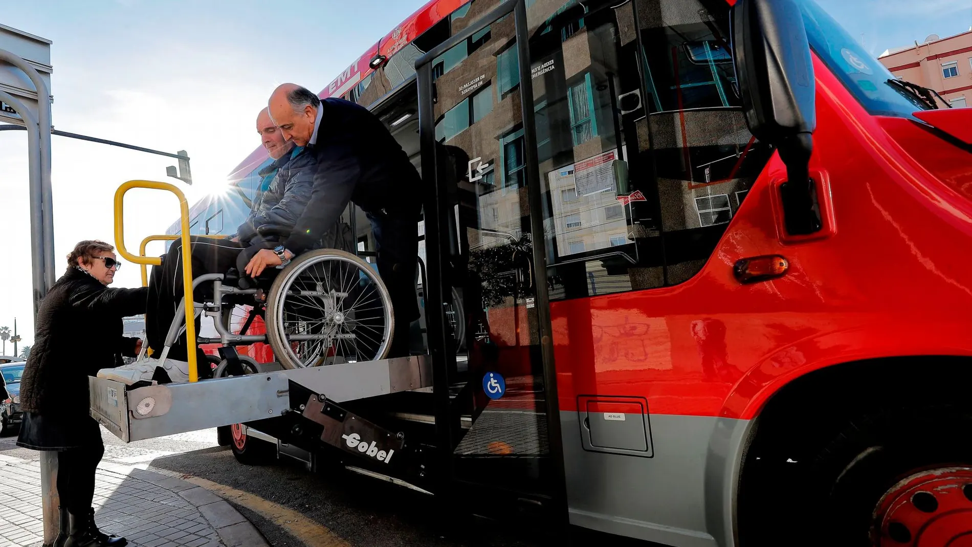 Serafín, conductor del servicio especial "puerta a puerta"de la EMT, ayuda a Juan a bajar del autobús adaptado. El servicio "puerta a puerta"que la EMT Valencia ofrece a personas con discapacidad se automatiza con una nueva aplicación móvil para que los usuarios que necesiten un transporte especial lo tengan a un "solo clic", casi en tiempo real y si tener que solicitarlo hasta 48 horas antes. EFE/Manuel Bruque