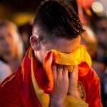 Un joven se cubre la cara con la bandera de España tras conocer la eliminación de Madrid.