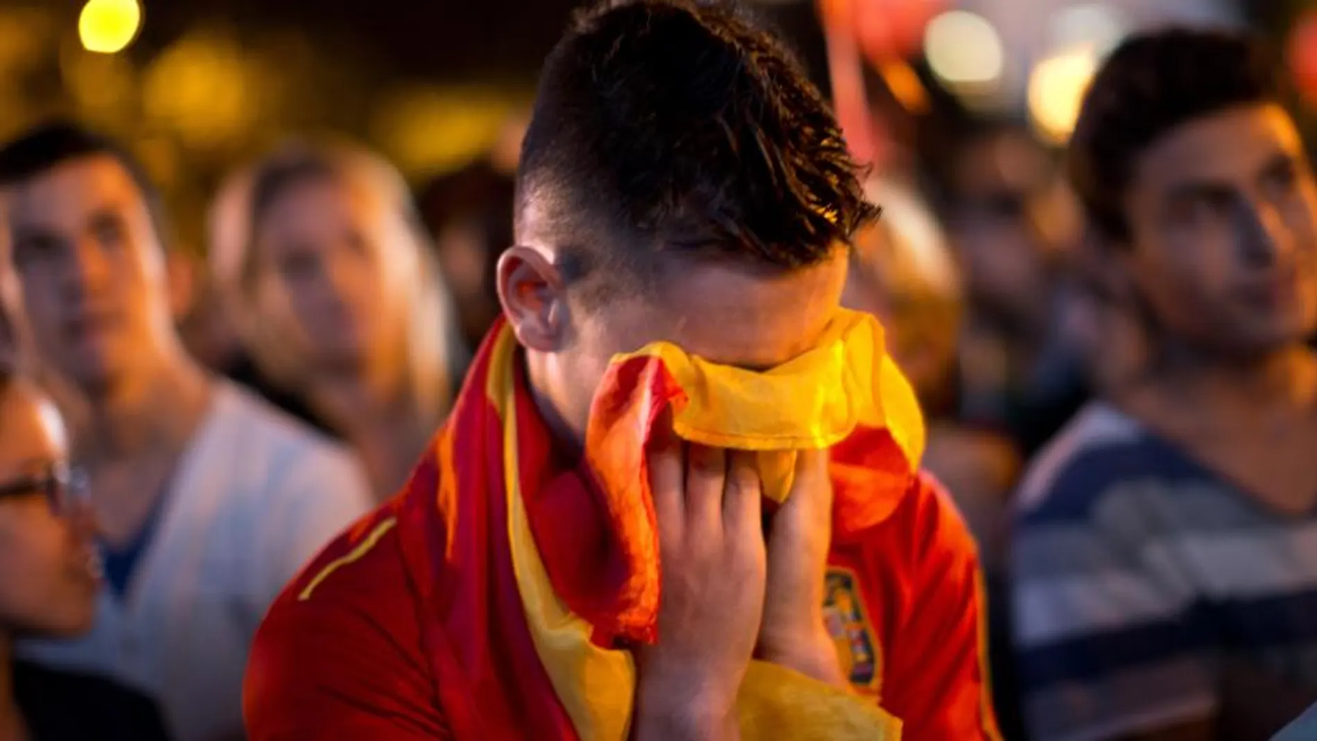 Un joven se cubre la cara con la bandera de España tras conocer la eliminación de Madrid.