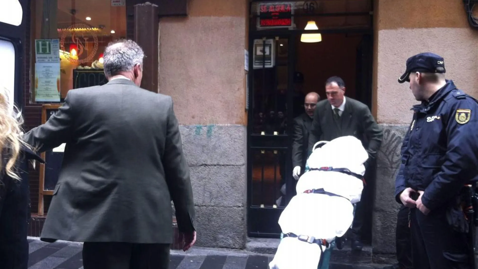 Miembros de los servicios funerarios trasladan el cadáver del hombre que ha recibido 14 puñaladas