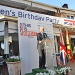 El embajador británico, Giles Paxman, escoltado por las banderas de España y Gran Bretaña, dirigiéndose a sus invitados por el día del cumpleaños de la Reina Isabel II.
