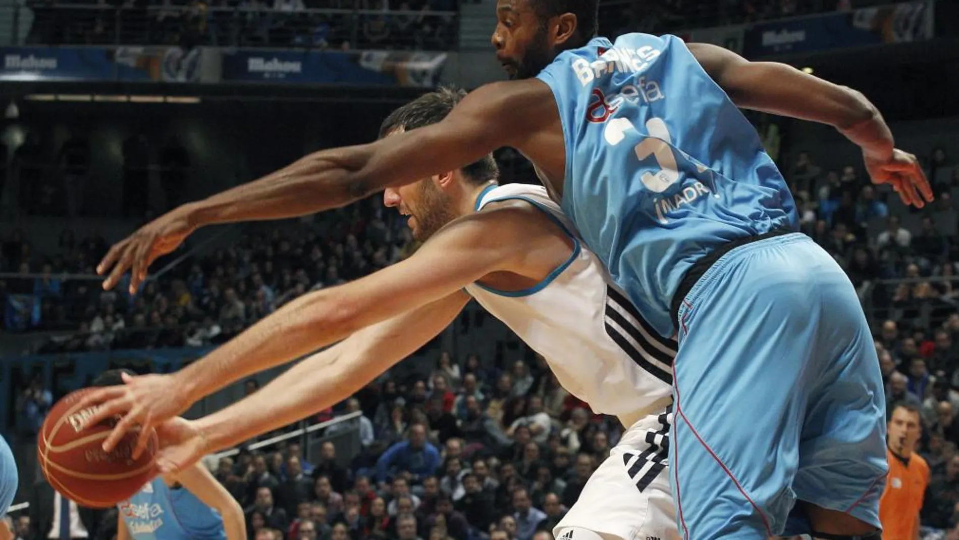 El pívot esloveno del Real Madrid Mirza Begic protege el balón ante el pívot estadounidense del Estudiantes Lamont Barnes