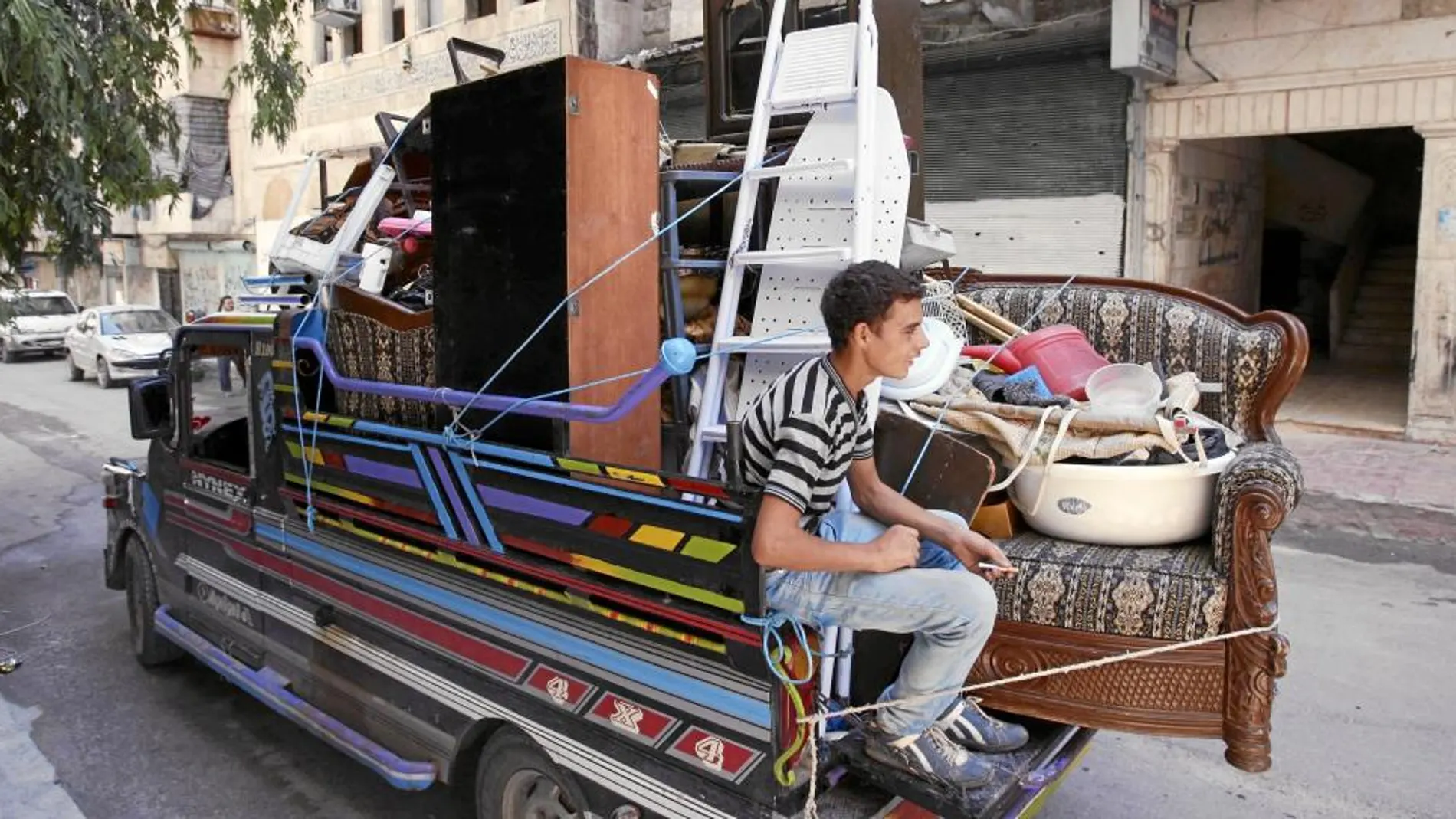 Una familia siria abandona su casa en el barrio Salah al Din, en el centro de Alepo, en un camión cargado con todas sus pertencias