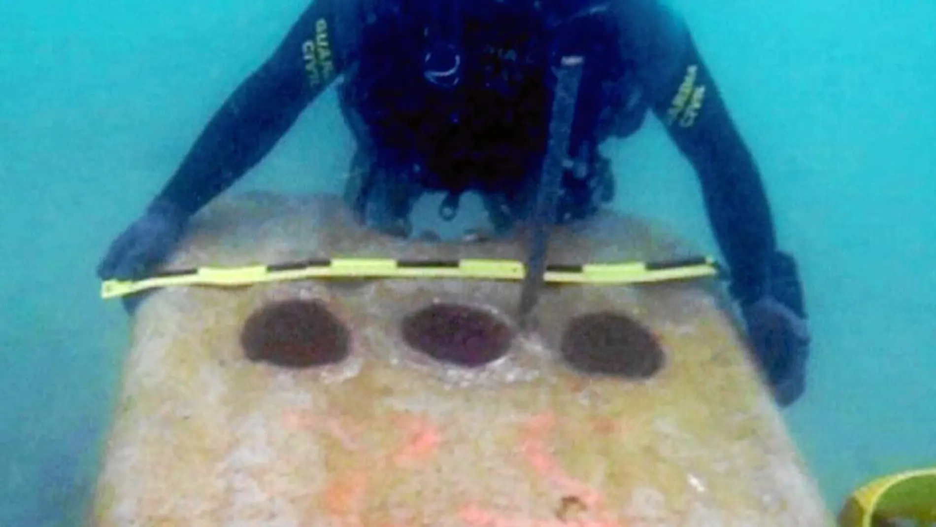 Un guardia civil mide uno de los bloques arrojados al fondo del mar por las autoridades del Peñón