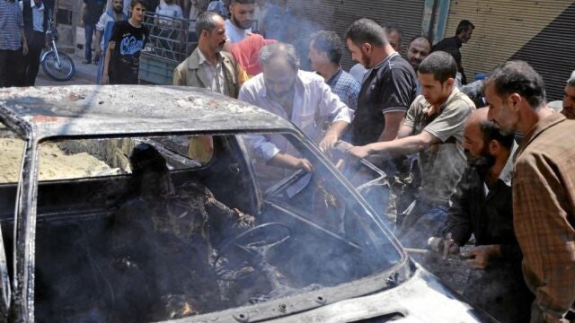 Un grupo de sirios trata de sacar a un hombre quemado en un ataque en Damasco perpetrado por las fuerzas leales a Asad
