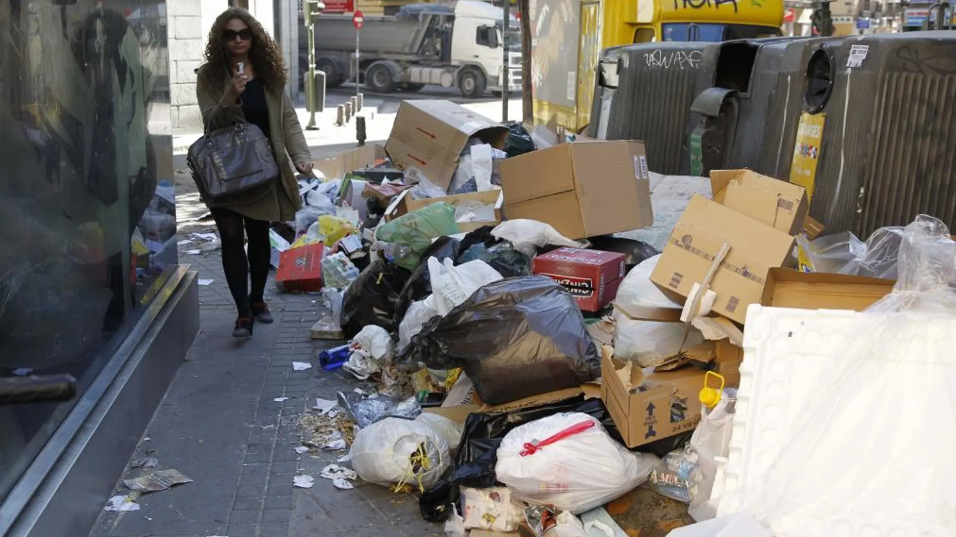 Una mujer pasa entre la basura amontonada en la calle Amaniel