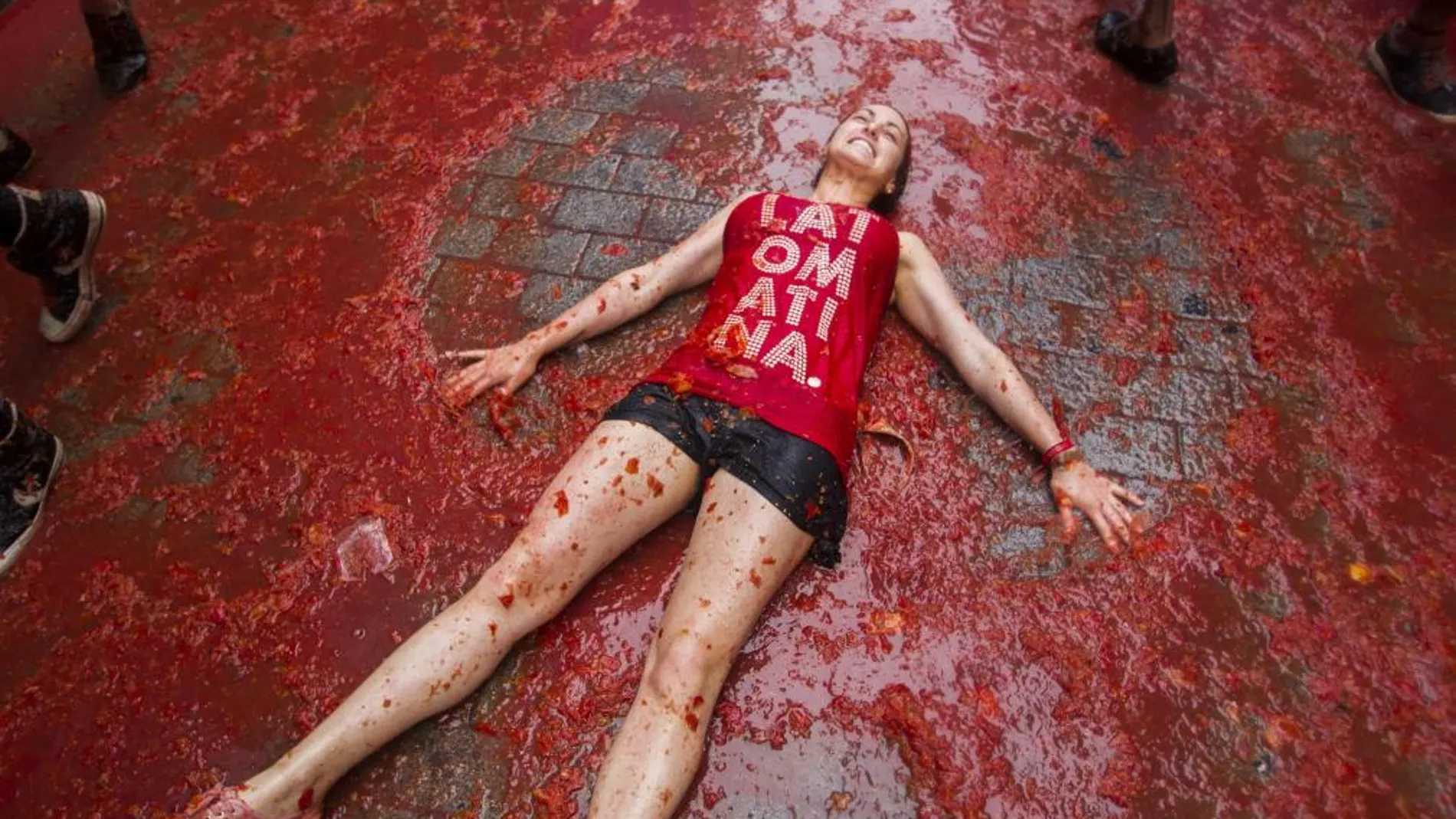 Una chica tendida en el suelo teñido de rojo en la fiesta de la Tomatina